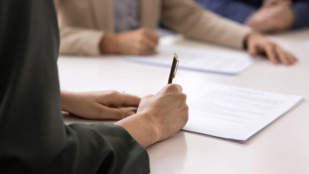 a woman signing a contract during a formal meeting