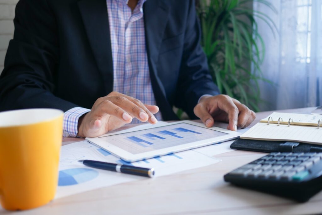 A businessman analyzing financial charts and data on a tablet at a desk with a calculator and notebook.
